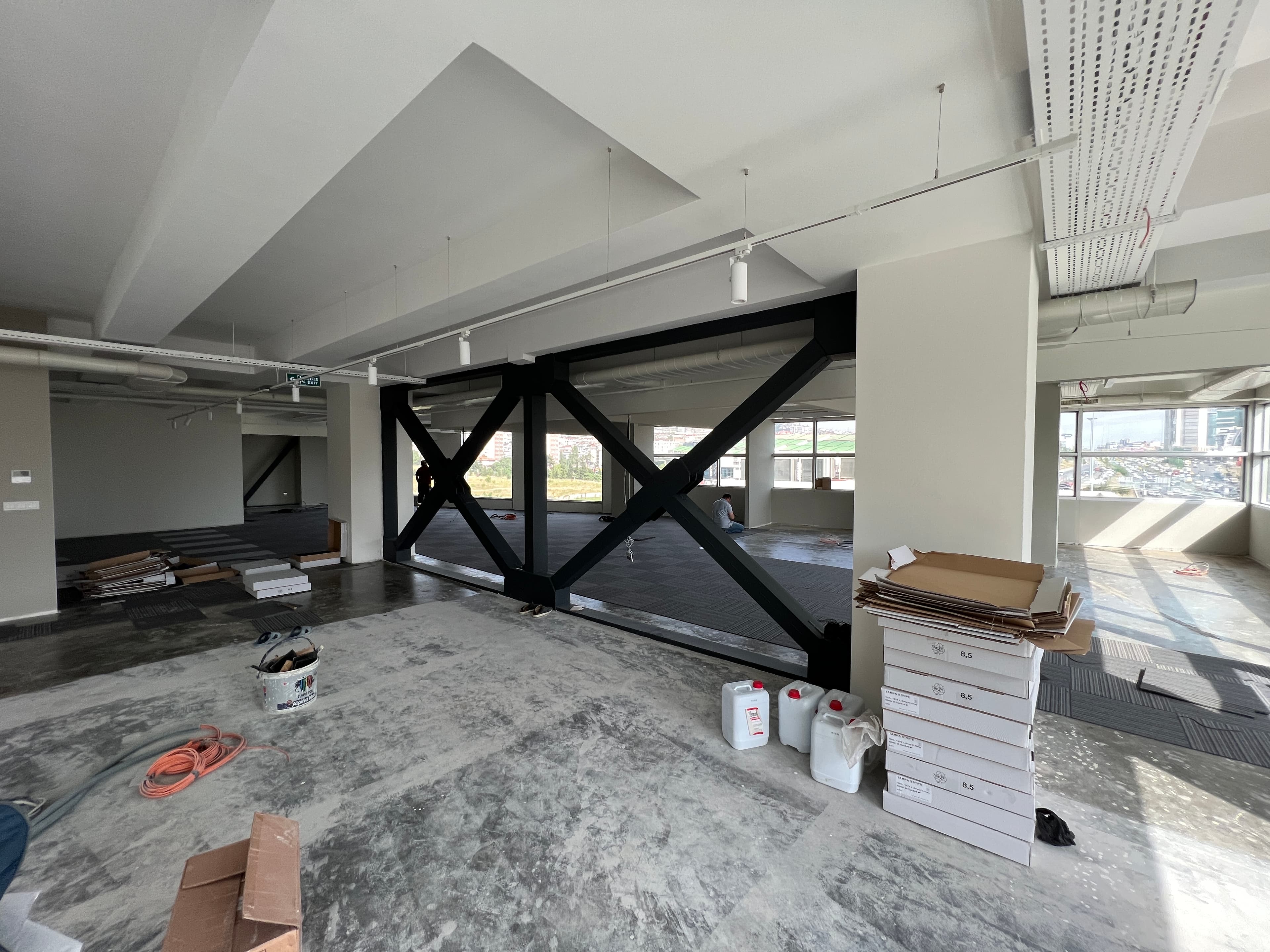 Construction showing steel cross-bracing with carpet tile installation starting