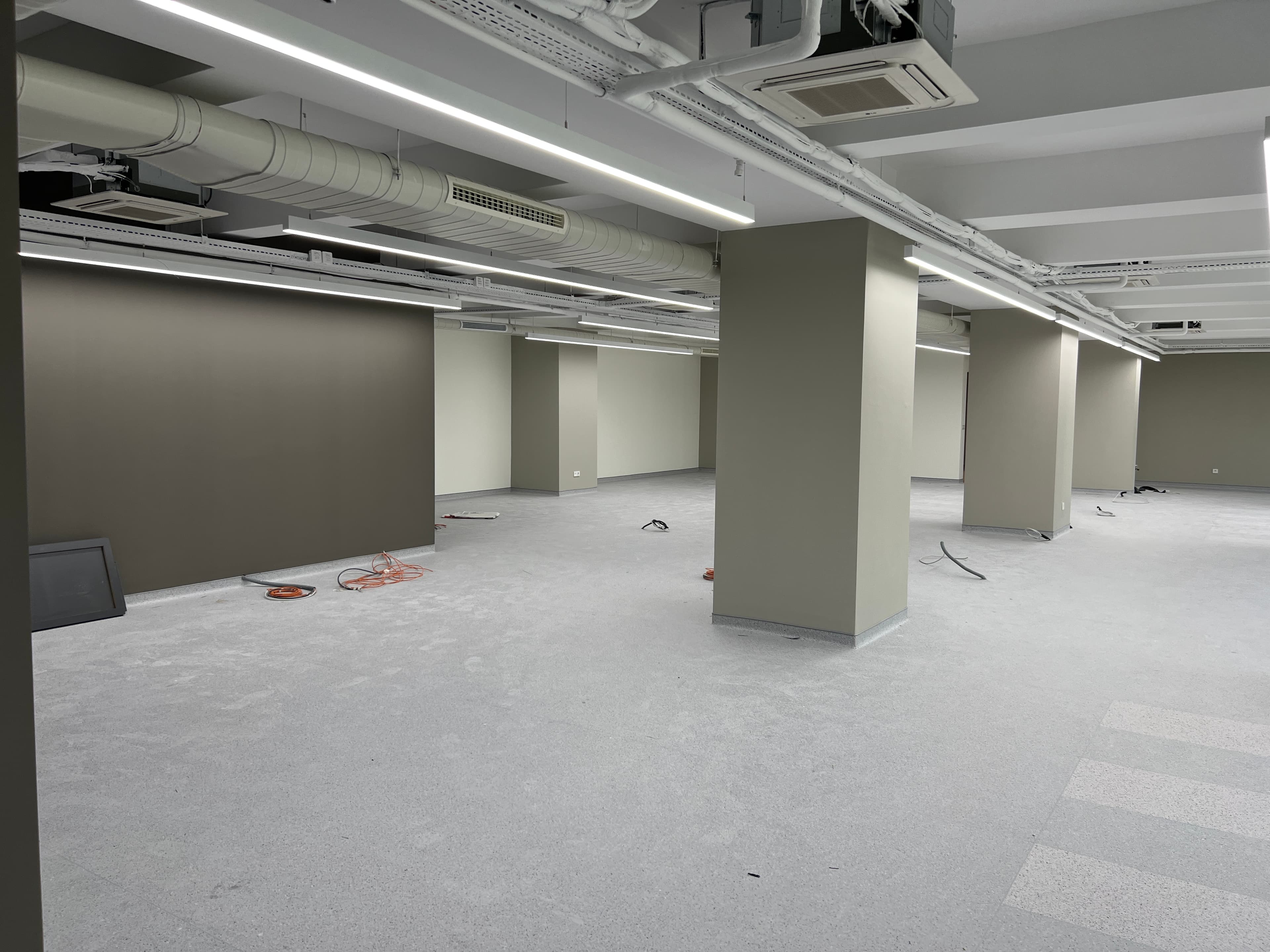 Construction area with dark green walls, columns, and exposed ceiling grid