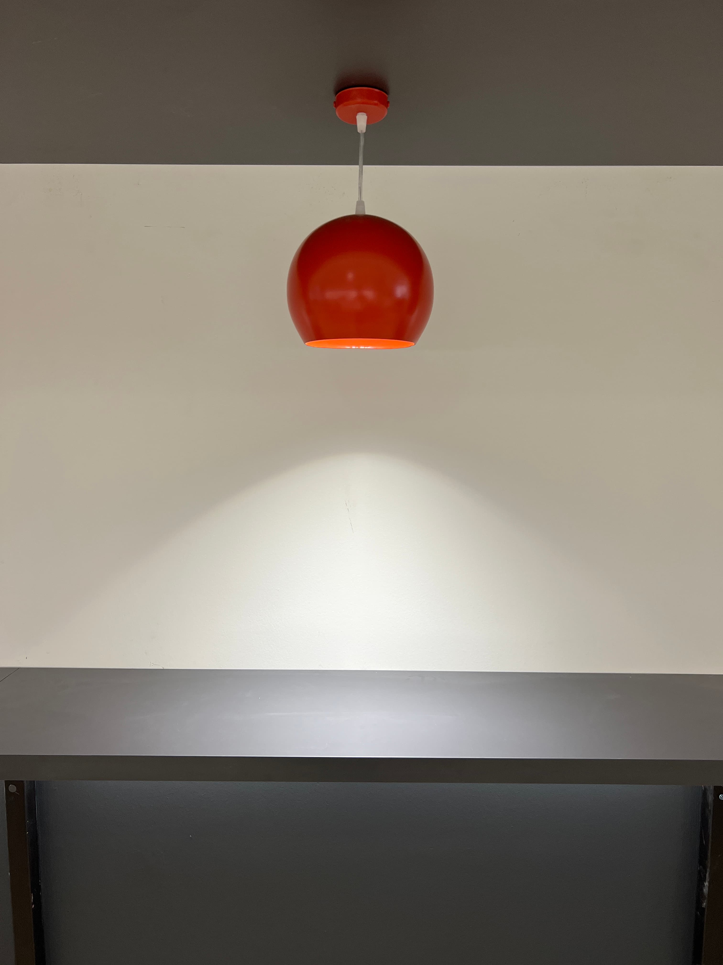 Close-up of red spherical pendant light against a dark wall