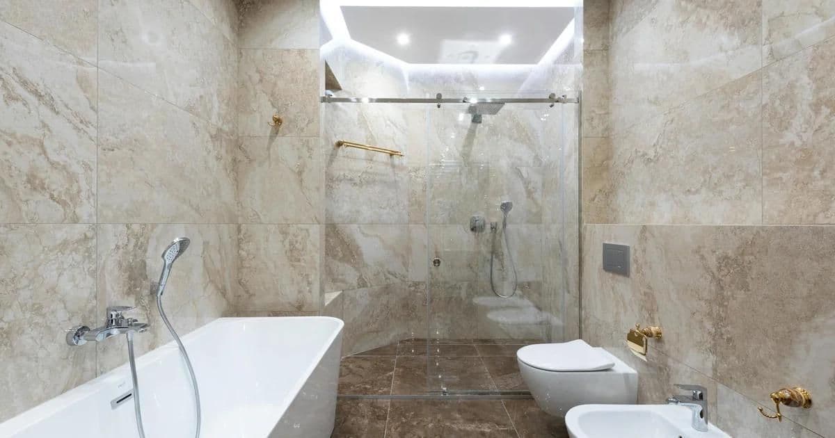 Ayaklı taş küvet, doğal taş duvarlar ve sıcak ortam aydınlatmasıyla lüks banyo